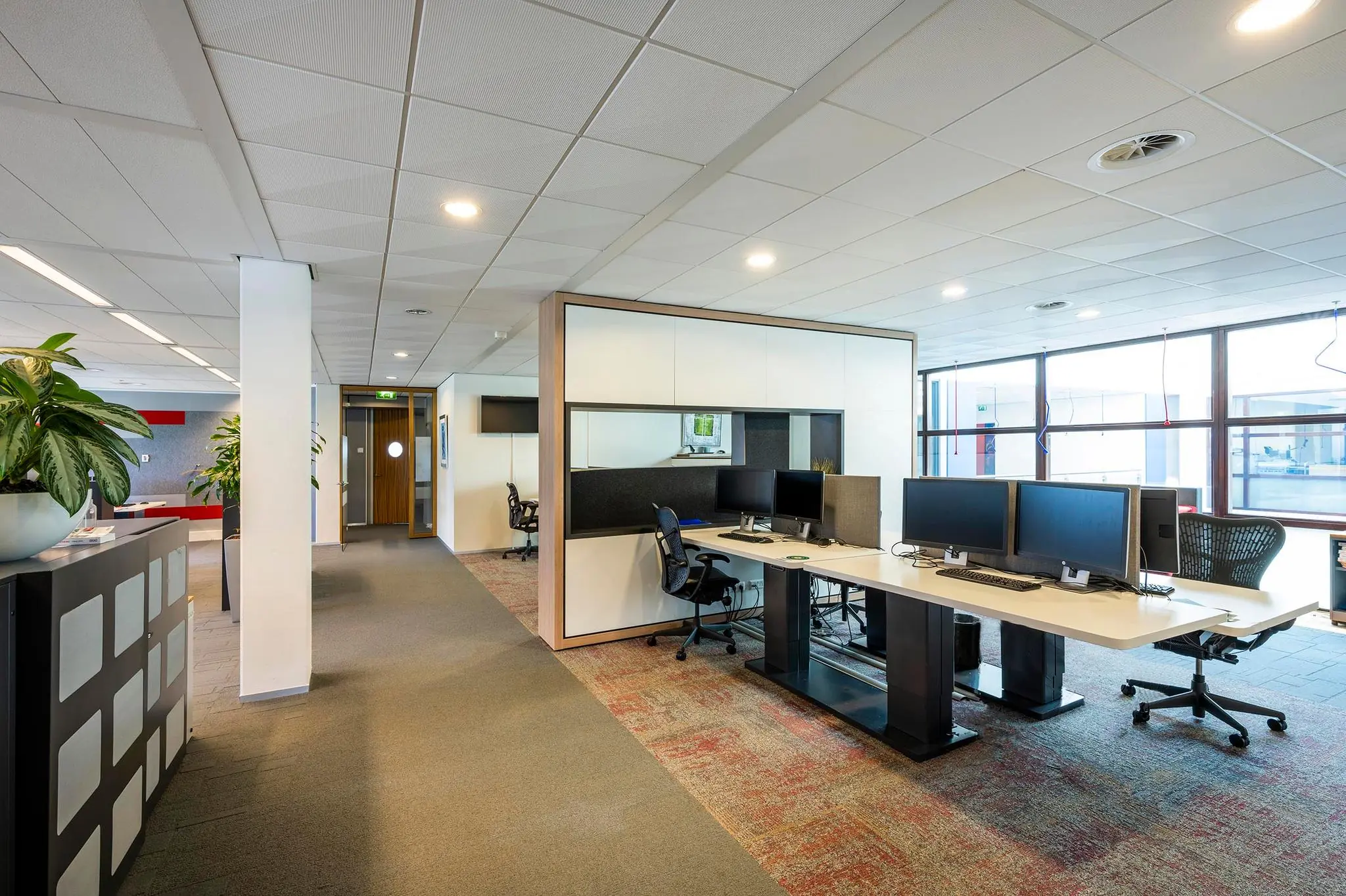 Modern kantoorpand aan de K.P. van der Mandelelaan met open werkplekken en bureaus met meerdere beeldschermen.